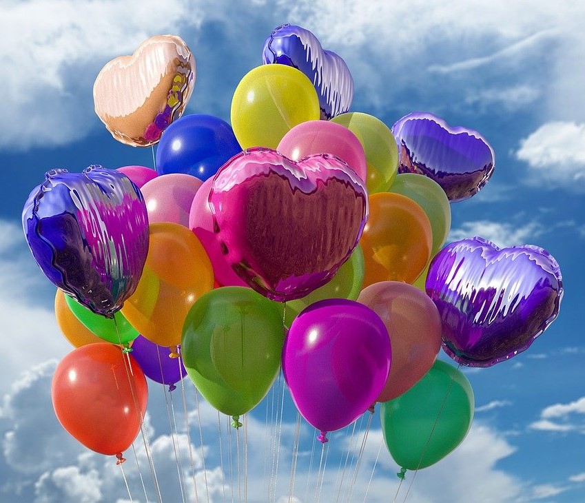 Dekorativ bild. Ballonger i olika färger mot en blå himmel med vita moln.